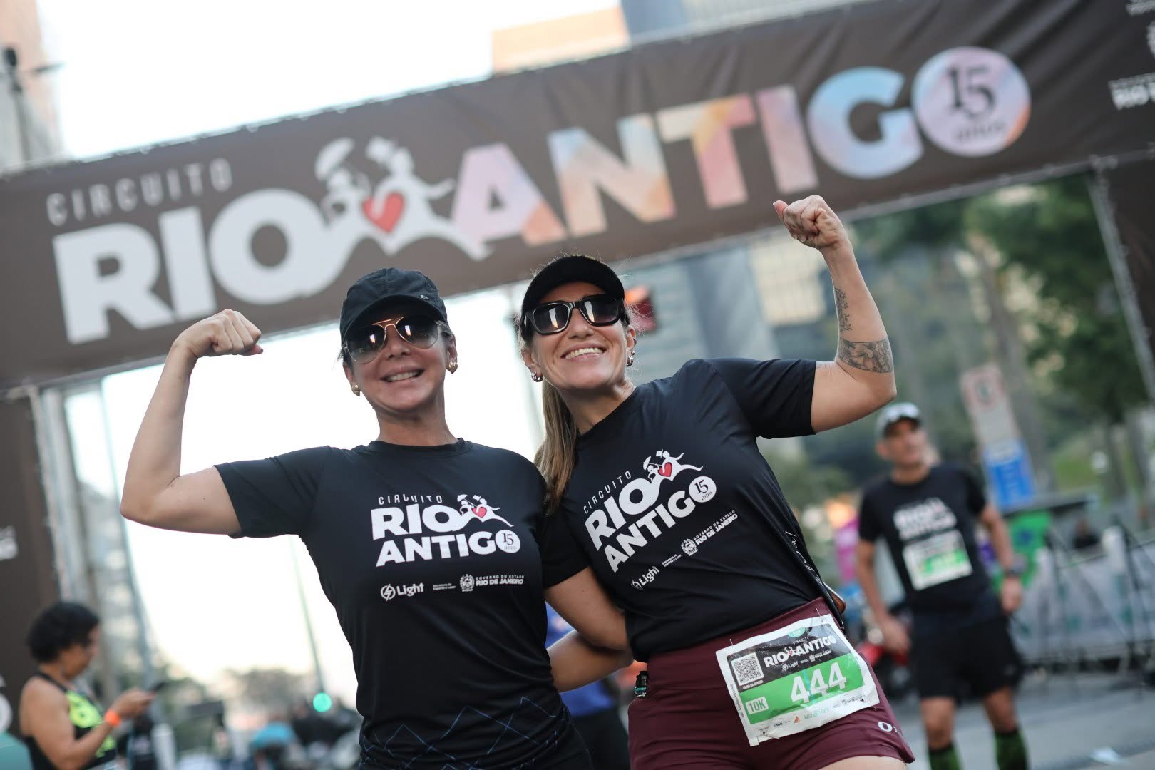 Duas atletas comemorando na chegada, sob o pórtico dos 15 anos do Circuito Rio Antigo